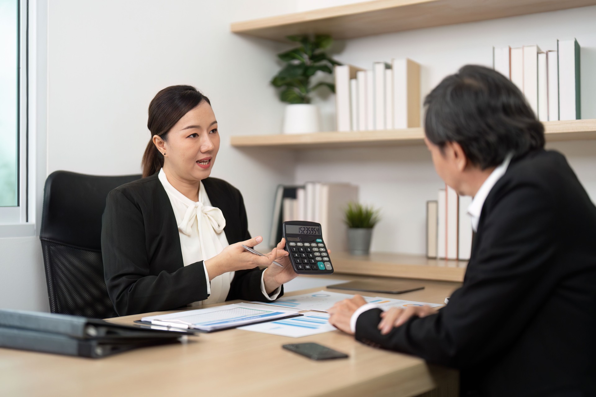 Business Consultation and Financial Planning. Professional woman discussing financial data with a client.